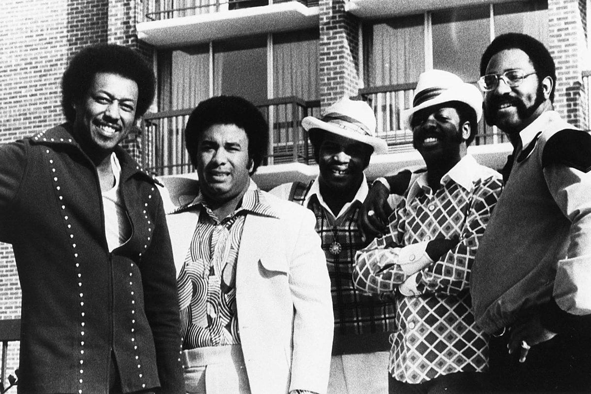 The Spinners pose in front of an apartment building in the 1970s