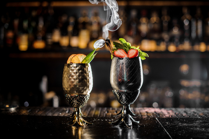 Metal glasses of fresh summer cocktails decorated with fruit on the bar counter
